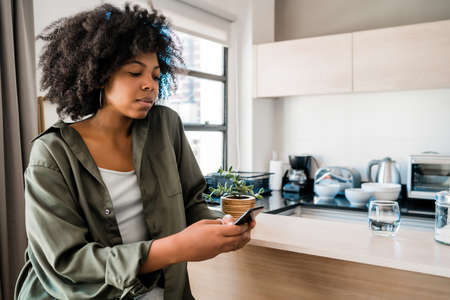 Afro woman using phone at home.の写真素材