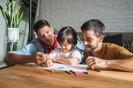 Gay couple and their son having fun together while drawing at home.