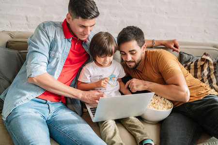 Two parents and their son watching a movie together at home.の写真素材