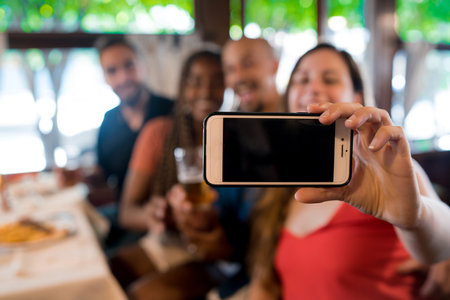 Group of friends taking a selfie with a mobile phone in a bar.の写真素材