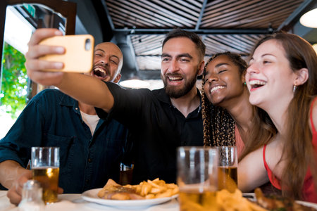 Group of friends taking a selfie with a mobile phone at a restaurant.の写真素材