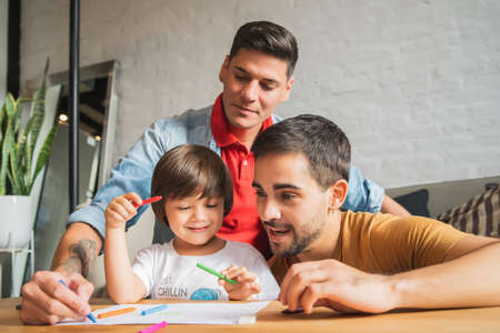 Gay couple and their son having fun together while drawing at home.の写真素材