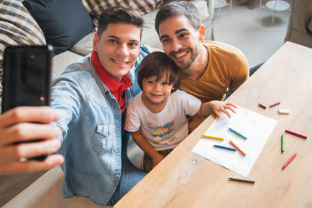 Gay couple taking a selfie with their son at home.の写真素材