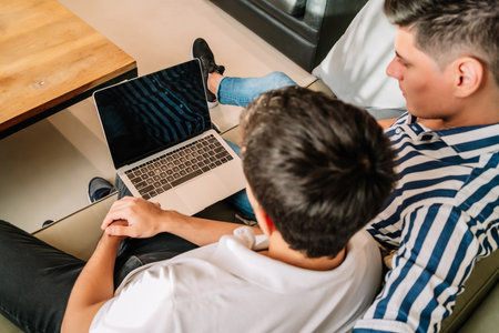 Couple using a laptop while sitting on a couch at home.の写真素材