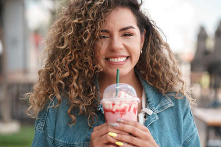 Young woman drinking a cold drink beverage at a coffee shop.の写真素材
