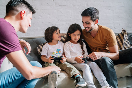 Gay couple playing video games with their kids at home.