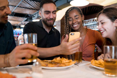 Group of friends using a mobile phone at a restaurant.の写真素材