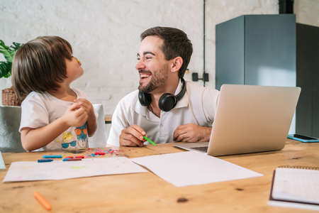 Man working from home while taking care of his son.