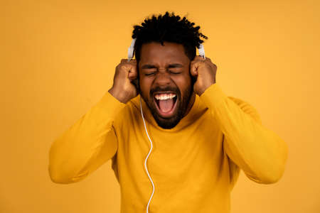Afro man enjoying listening music with headphones.