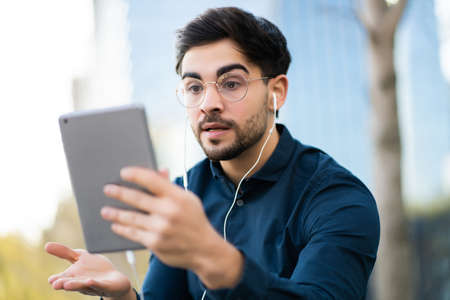Young man having a video call on digital tablet outdoors.の写真素材