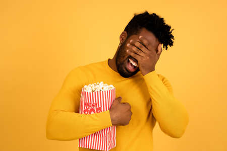 Afro man eating popcorn while watching movies.の写真素材