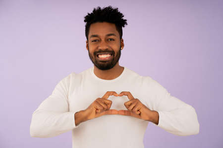 Afro man smiling while making a heart with her hands.