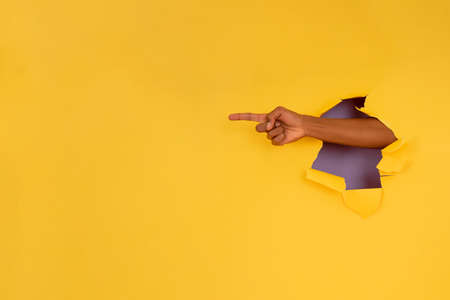 Finger pointing something through a hole in a paper wall.の写真素材