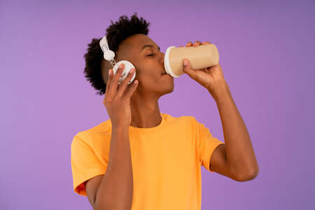 Afro man drinking coffee while listening music with headphones.の写真素材