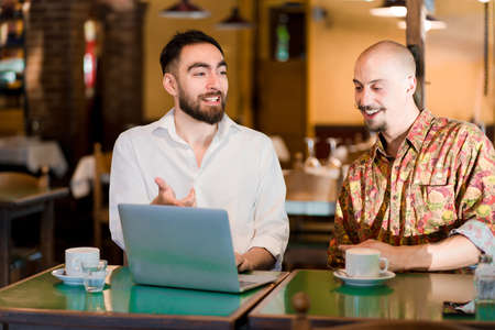Two people using a laptop on a meeting at a coffee shop.の写真素材