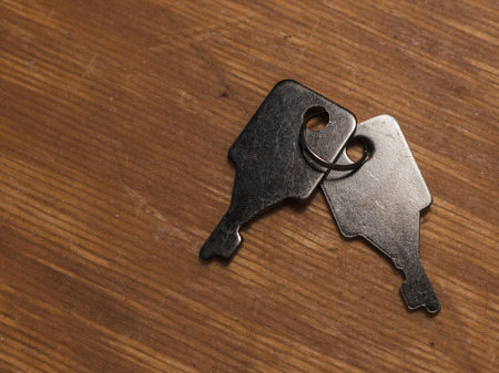 Two small keys on the old and dirty wooden table with a lot of scratches. Image with copy space.
