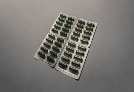 4 blisters of green medicine drugs lying one on the cardboard