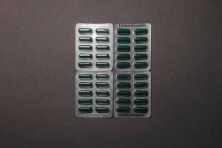Four blisters of green medicine drugs squared on a cardboard