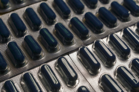 Pharmaceutical background of dark blue pills in blisters. The blisters of dark blue medicine drugs and bills lying near each otherの写真素材