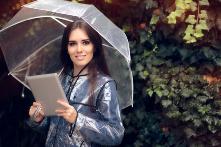 Smiling Woman with Raincoat and Umbrella Holding Pc Tablet Smiling Woman with Raincoat and Umbrella Holding Pc Tablet