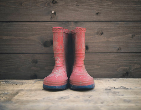 a couple of red baby galoshes in wood backgroundの写真素材
