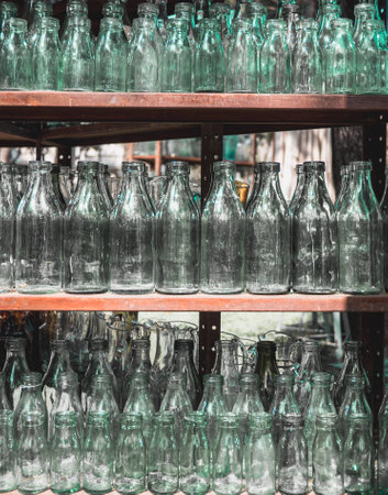 lots of vintage transparent glass bottles on three shelvesの写真素材
