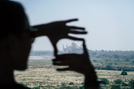 Girl making a picture frame of the Taj Mahal on an early morning in Agraの写真素材