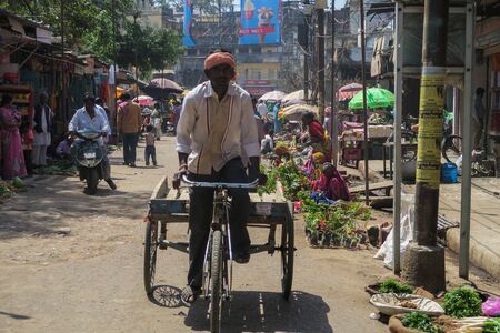 Varanasi, India - March 25, 2017, Travelling through India: Street scene with riksha bicycle and market sellersのeditorial素材