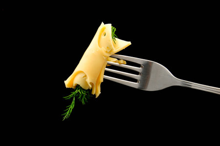 cheese and dill on a fork on black backgroundの写真素材