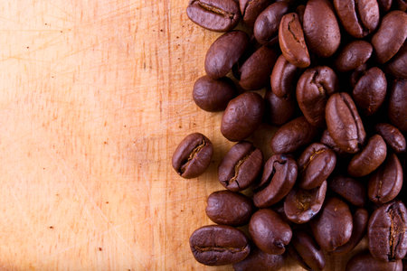 roasted coffee beans lying on a wooden board closeupの写真素材