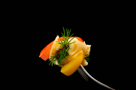 cheese, tomato and dill on a fork on black background