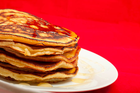 delicious pancakes with honey sauce on red backgroundの写真素材