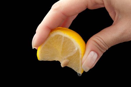 squeeze lemon juice on hand for the black backgroundの写真素材