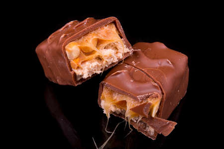 two slices of Snickers bars on a black background macro