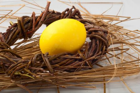 yellow Easter egg in a wicker wreathの写真素材