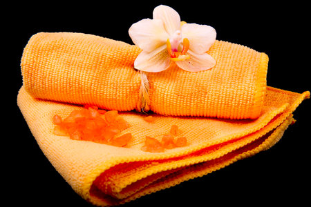 flower yellow-orange orchids and orange towel on glossy black backgroundの写真素材