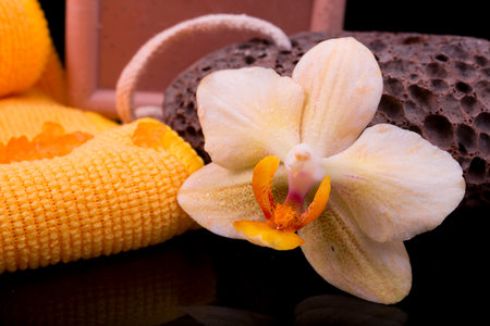 flower yellow-orange orchids and orange towel on glossy black backgroundの写真素材
