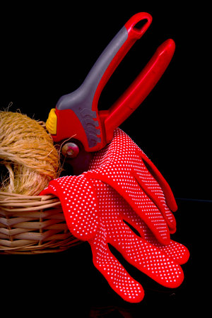 the composition of the basket for the garden, pruning shears, gloves and rope on a black background