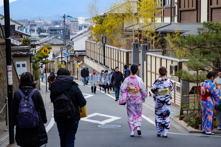 KYOTO, JAPAN - 08 FEB 2018: Two colorful young japanese girls dressed in traditional kimonos walking down a street in Gionのeditorial素材