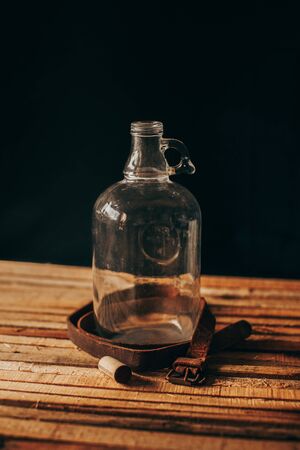 Vintage wooden stage, glass vase, rusty metals, old leather and rusty tools on a black background