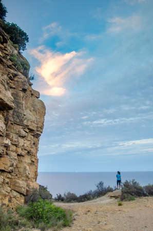 Woman looking the sunset at the Mediterranean sea from a cliffの写真素材