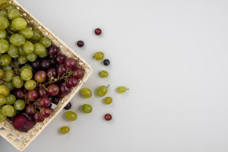 top view of fruits as pluot and grapes in basket and grape berries on white background with copy spaceの写真素材