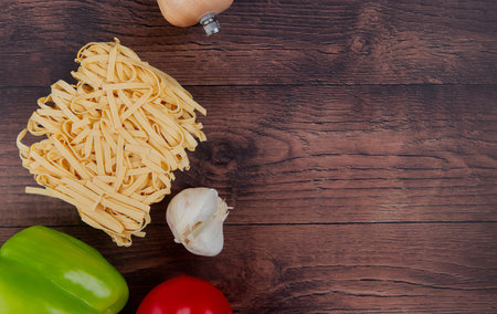 top view of macaronis as tagliatelle ziti with pepper garlic tomato on wooden background with copy spaceの写真素材