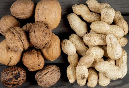 top view of nuts peanuts in shell and whole walnuts on wooden background