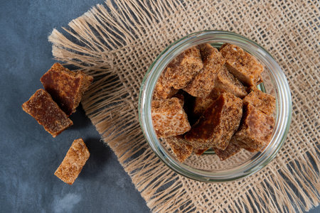 top view of palm sugar cubes in a glass jar on sackcloth texture backgroundの写真素材