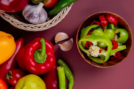 top view of pepper slices in bowl with vegetables as pepper tomato in basket with garlicの写真素材