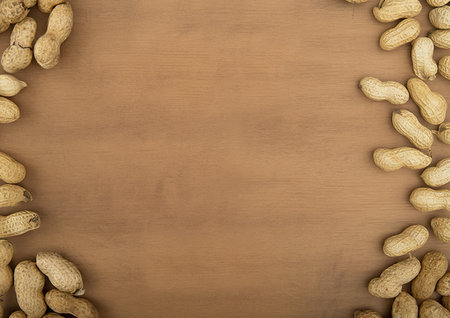 top view of peanuts in shell scattered on wooden background with copy space