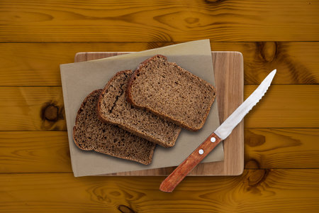 top view of rye bread slices and knife on cutting board on wooden background