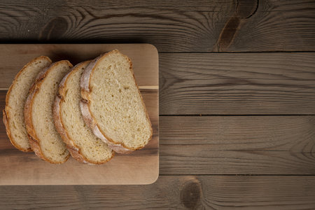 top view of sliced crusty bread on cutting board on wooden background with copy spaceの写真素材
