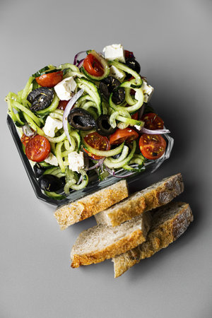 Greek salad with bread in a glass container